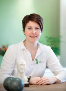 Therapeutin, sitzend am Tisch in Ihrer Praxis fotografiert.