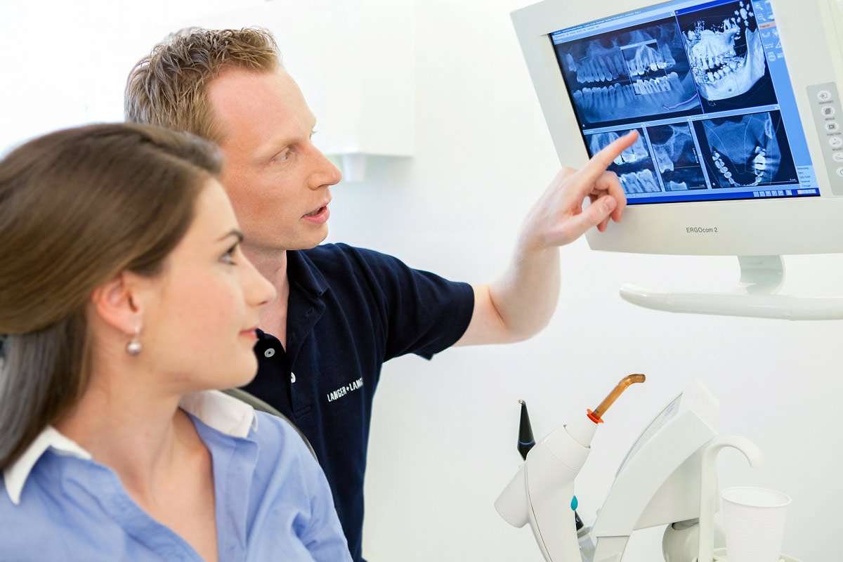 Arzt erklärt am Monitor das Röntgenbild, Praxisfoto