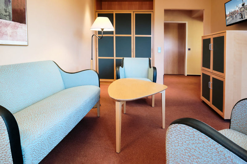 Hotelfotografie des Zimmers. Couch Tisch und Sessel.