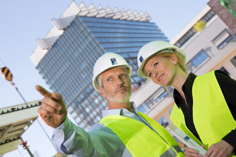 Mann und Frau mit Warnweste und Helm auf Baustelle in Köln.