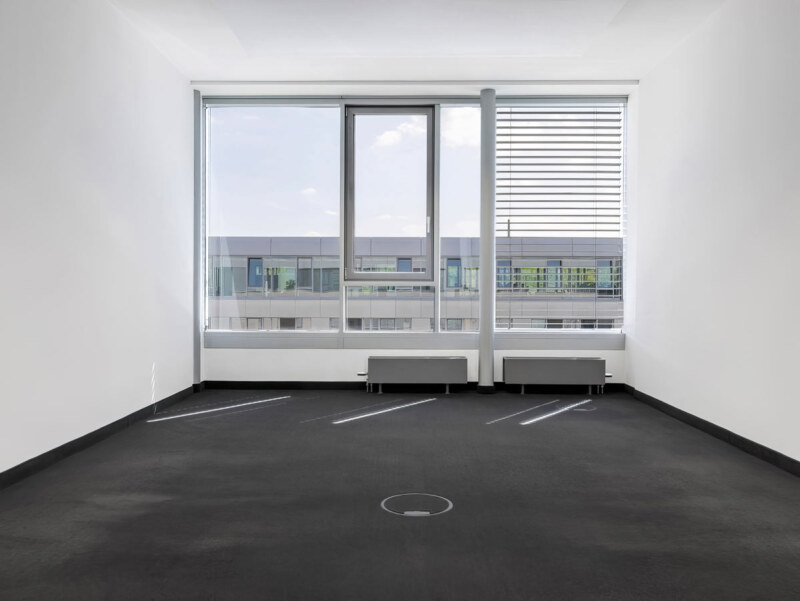 Heller Büroraum mit großer Fensterfläche und dunklem Teppich. Ein Raum Foto des Immobilien Fotografen für den Raum Köln, Bonn und Düsseldorf.
