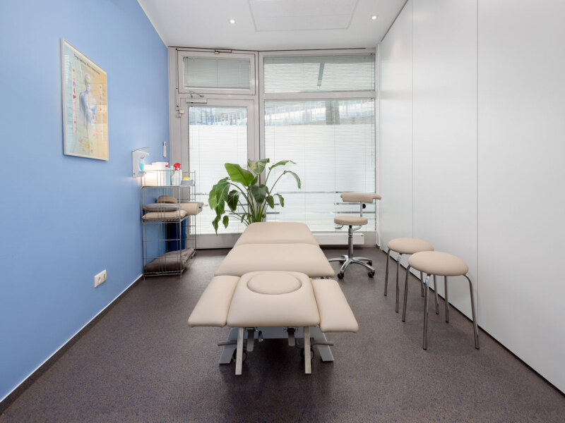 Physio Behandlungsraum mit Liege, Stuhl, Hockern und einem Regal. Ein Praxis Foto des Fotografen für Praxisräume