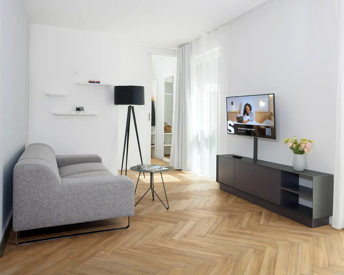 interior-hotelfotograf-plz Ein großzügiges Hotelzimmer mit begehbarem Kleiderschrank, großem Fernseher und Couch.